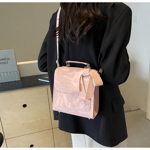 Detailed back view of pink crossbody bag with bow decoration on pleated leather material