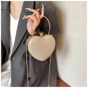 Detail of champagne gold heart clutch featuring glitter finish and gemstone clasp