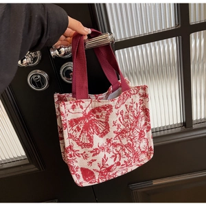 Detail of a vintage floral knit tote bag with red butterfly print and sturdy ribbon handles