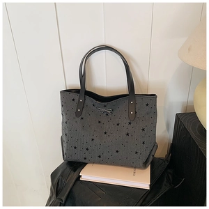 Macro detail of star pattern wool tote bag with a silver bow clasp and leather handles