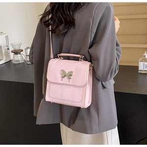 Vue détaillée du sac en cuir rose avec boucle papillon argentée sur une veste grise