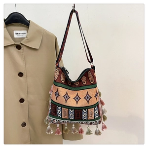 Close-up of bohemian tote bag with woven geometric patterns and colorful tassels