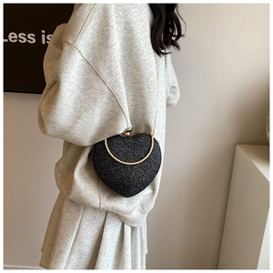 Detail of heart-shaped black glitter bag with gold top handle and elegant chain strap