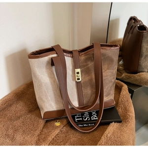 Detail of color-block canvas tote bag with brown leather trim and golden twist lock