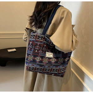 Ethnic style woven canvas bucket bag shown on shoulder over a khaki trench coat