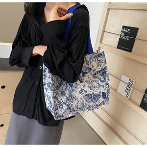 Detail of floral butterfly print on a large knit tote bag worn by a model