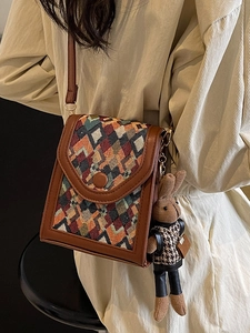 Vertical geometric woven crossbody phone bag with a cute knit rabbit charm on a model