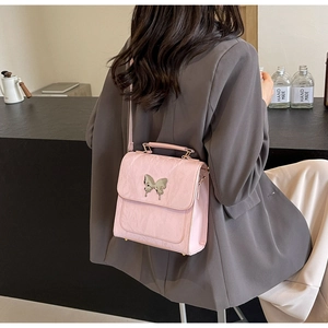 Sac rose à texture plissée et boucle papillon argentée porté par un mannequin