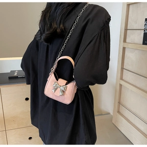 Back view of model wearing mini pink leather crossbody bag with silver bow and chain