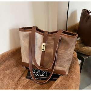 Detail of canvas tote bag showing the gold twist lock closure and brown leather trim