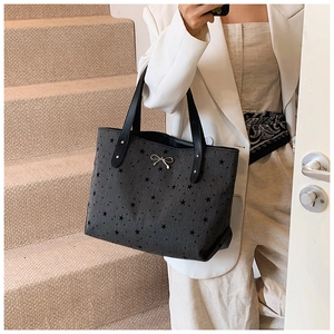 Detail of star-patterned tote bag featuring a silver metal bow and leather handles