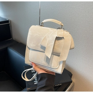 Detailed view of the large decorative bow and textured leather on the cream white shoulder bag