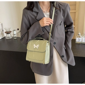 Détail du sac à bandoulière vert clair avec texture marbre et boucle papillon argentée