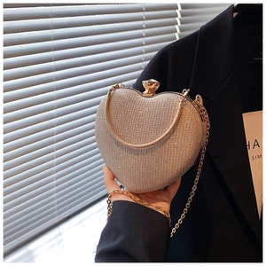 Close-up of heart-shaped clutch with champagne rhinestones and jewel clasp on black suit