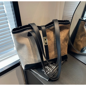 Detail of two-tone tote bag with gold twist-lock closure on black leather strap