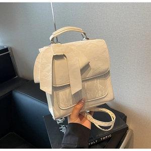 Close-up of white fashion backpack featuring a large bow detail and pleated texture