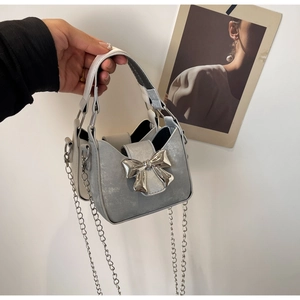 Detail of silver mini bag featuring a large metallic bow and elegant chain strap