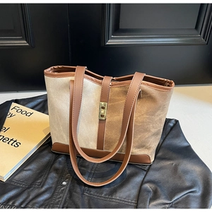 Detail of color-block canvas tote bag with brown leather trim and golden metal clasp