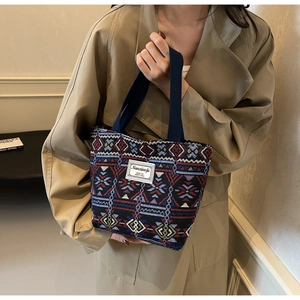 Detail of colorful geometric woven tote bag with sturdy handles and white brand label