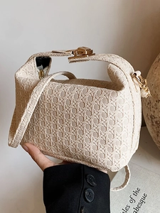 Cream woven handbag with gold hardware clasp and crossbody strap in hand view