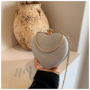 Detail view of heart-shaped silver glitter clutch with gold chain and sphere clasp