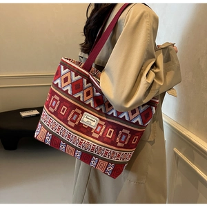 Detail of bohemian woven tote bag with geometric patterns and a wide dark red shoulder strap