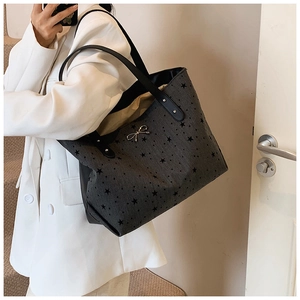 Detail of grey tote bag with black star prints and a silver bow hardware accent