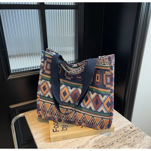 Detailed close-up of ethnic woven tote bag with geometric tribal patterns on a stone surface