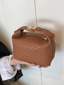 Brown woven box handbag with gold hardware and crossbody strap in a modern minimal style