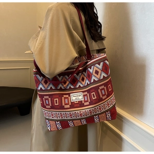 Detail of vintage patterned canvas bucket bag with wide red strap on trench coat model