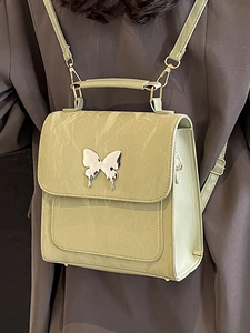 Petit sac à dos vert pour femme avec décoration papillon sur une veste sombre