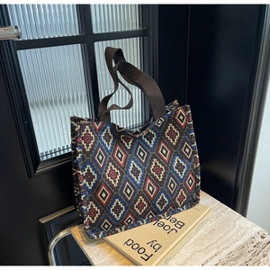 Close-up of ethnic tote bag with geometric woven patterns on natural stone surface