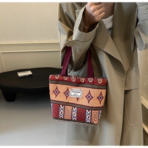 Detail of ethnic knit tote bag featuring diamond patterns and woven red handles