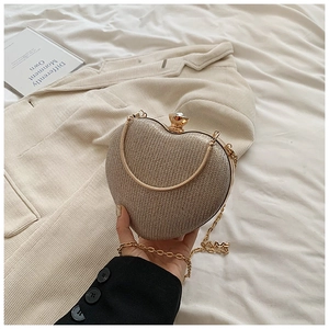 Detail of heart-shaped champagne gold evening clutch bag with crystal clasp and chain
