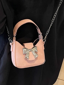 Pink mini crossbody bag with a large silver bow and detachable chain shoulder strap