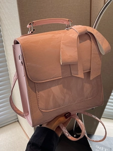 Chic pink patent leather bow shoulder bag with versatile straps and shiny metallic accents