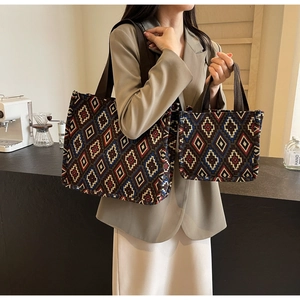Detail view of large and small retro geometric knit tote bag set in a cozy cafe setting