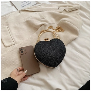 Macro view of heart-shaped glitter evening bag with gold metal handle and chain strap