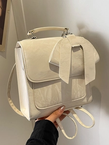 Elegant cream ruffled handbag featuring a large bow and adjustable crossbody strap
