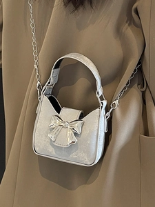 Silver glitter mini handbag with large metal bow and chain strap on brown blazer