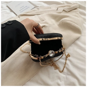 Detail of a black sequined evening clutch with gold trim and a large crystal clasp closure