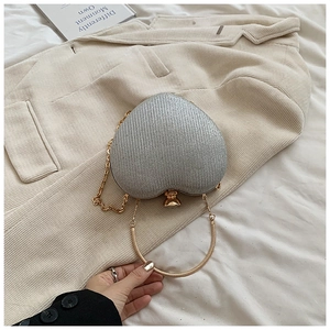 Detail of silver glitter heart clutch bag with gold handle and spherical clasp closure