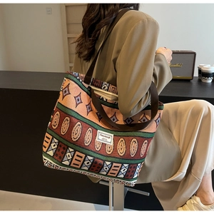Detail of bohemian woven tote bag with geometric patterns and brown wide shoulder strap