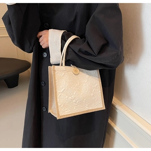 Detail of cream linen tote bag featuring rose floral jacquard texture and wooden button