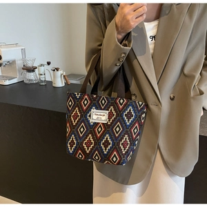 Detail of canvas bucket bag with geometric knit pattern worn by a model in a cafe