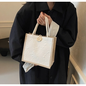 Detail of rose embossed jacquard fabric bag with wooden button and rope handle