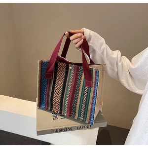 Detail of ethnic jacquard pattern and red woven handle on a canvas tote bag