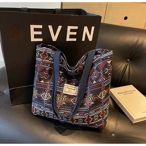 Close-up of ethnic geometric weave canvas bucket bag on black leather sofa