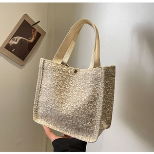 Gros plan du sac cabas beige montrant la texture jacquard florale et le fermoir aimant