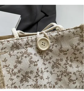 Dettaglio della borsa beige a fiori con grande bottone in legno e manico in corda spessa